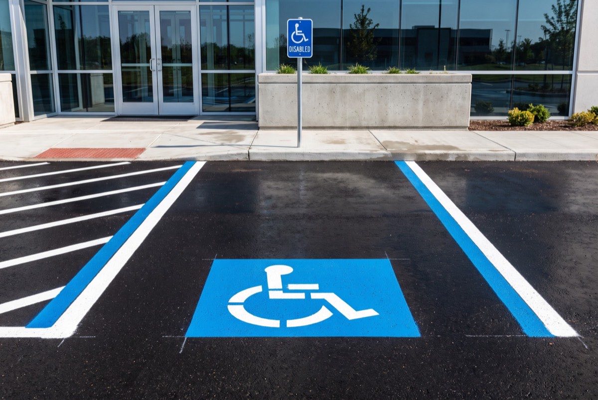 Freshly painted ADA accessible parking stall with wheelchair symbol, access aisle and signage